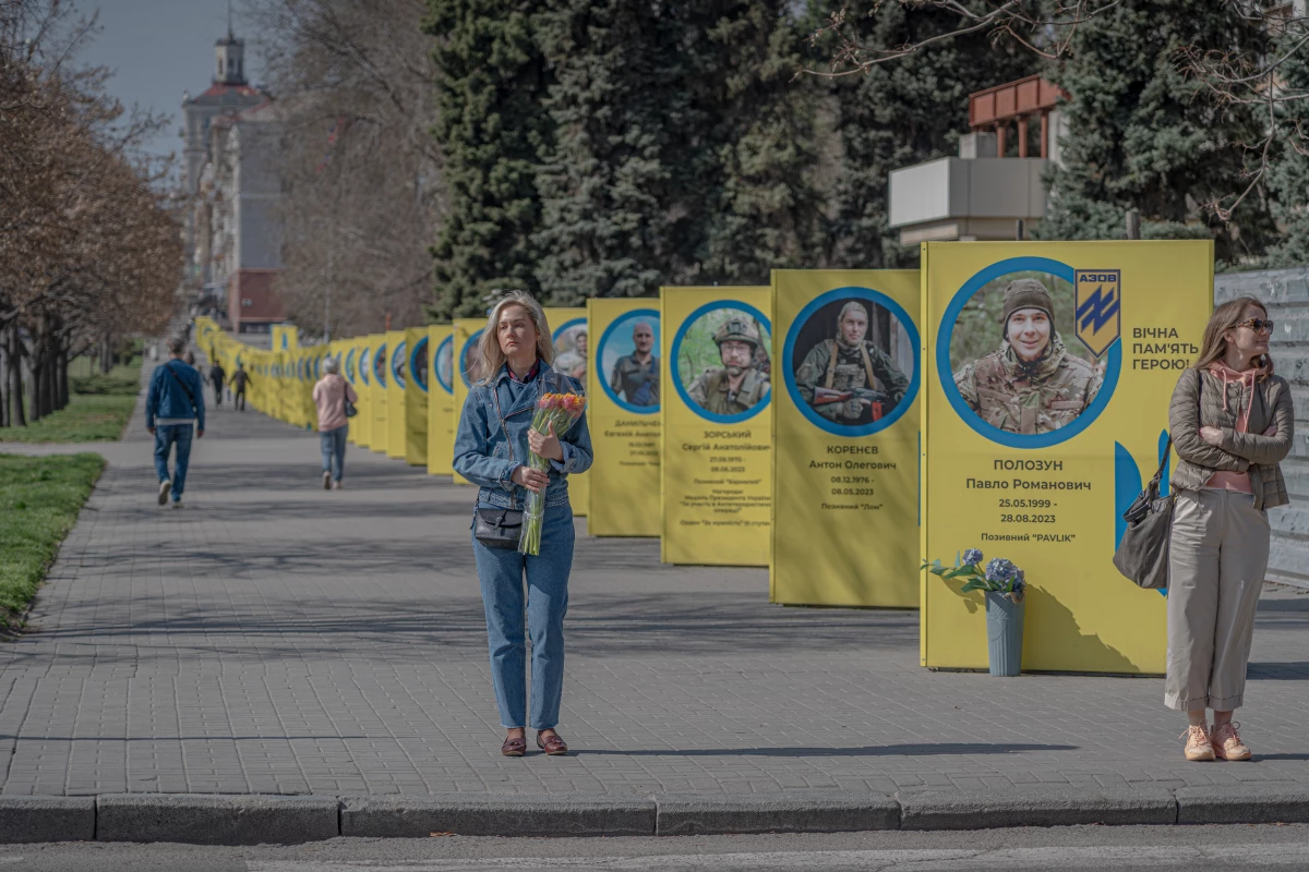 People walk down the street past banners commemorating fallen soldiers in Zaporizhzhia.