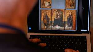 A journalist browses the Messina museum website showing a picture of the Early Renaissance painter Antonello da Messina's artwork where three of the five panels belonging to the Polyptych of San Gregorio and the double-sided panel with the Madonna and the Christ in Pietà, stolen from the Sicilian museum on Aug. 15, in Rome, Sunday, Aug. 16, 2026.