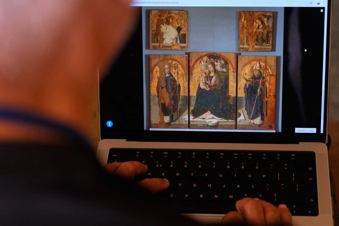 A journalist browses the Messina museum website showing a picture of the Early Renaissance painter Antonello da Messina's artwork where three of the five panels belonging to the Polyptych of San Gregorio and the double-sided panel with the Madonna and the Christ in Pietà, stolen from the Sicilian museum on Aug. 15, in Rome, Sunday, Aug. 16, 2026.