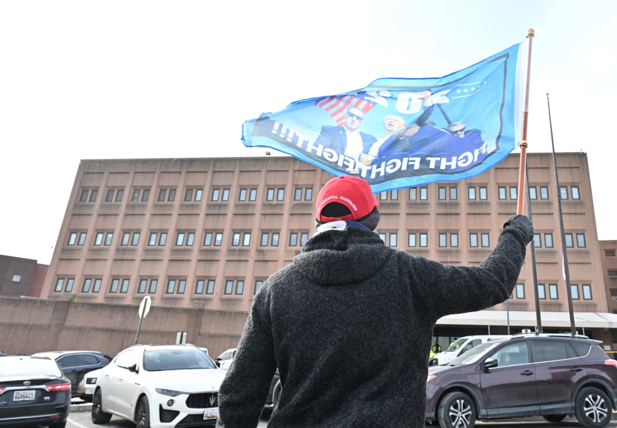 A supporter of President Trump's waves a flag Tuesday outside a Washington, D.C., jail where some defendants from the Jan. 6 attack on the U.S. Capitol were being held. On Monday, Trump signed pardons for more than 1,500 people charged in the riot.