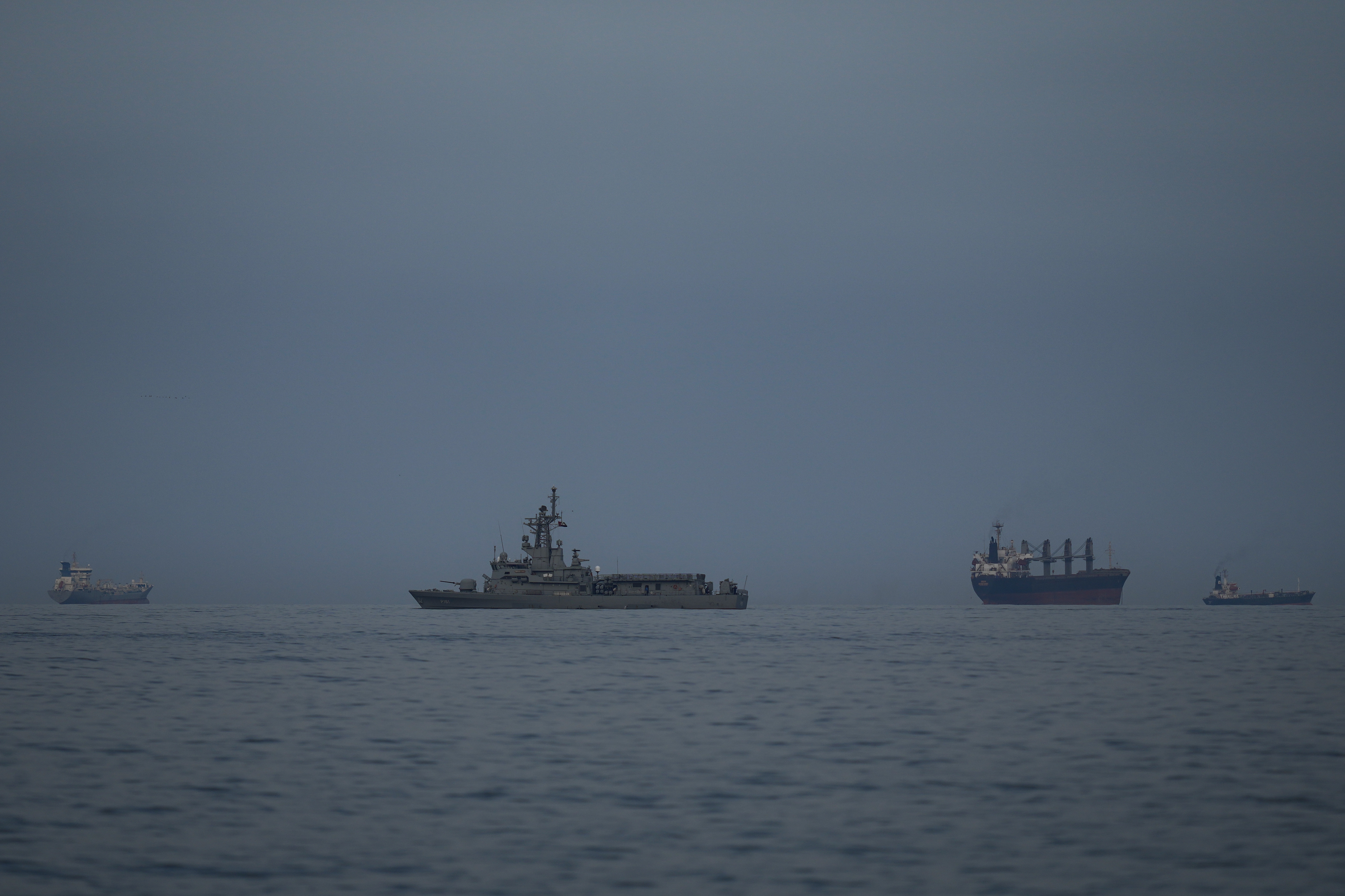 A United Arab Emirates navy vessel patrols next to cargo ships and oil tankers in the Strait of Hormuz, as seen from Khor Fakkan, United Arab Emirates, March 11. (AP)