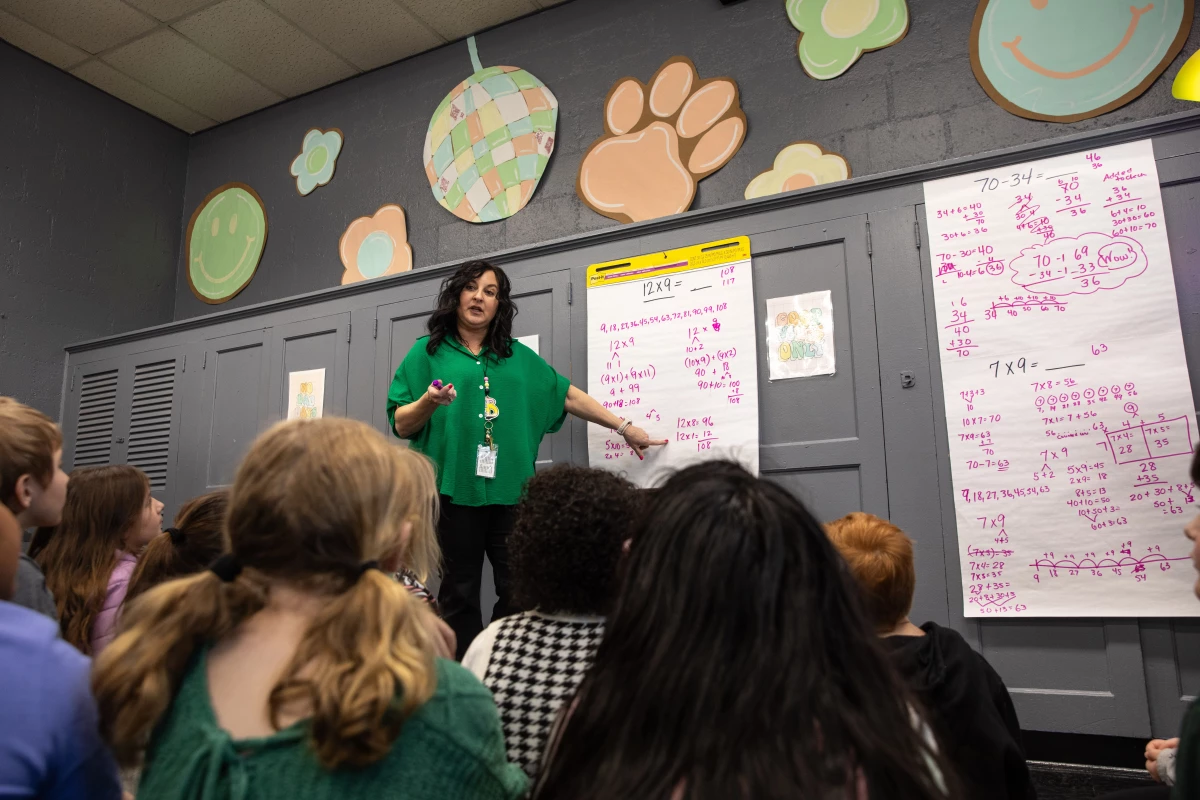 Third grade teacher Tracy Butts asks her students at Henagar Junior High School (K-8) how many different ways they can solve 12 x 9 without using pencil or paper. Together, they come up with five different possibilities.