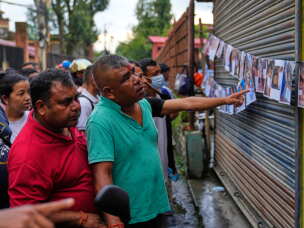 People look at photographs of people killed in flash floods displayed outside a government hospital to help relatives identify the victims in Kathmandu, Nepal