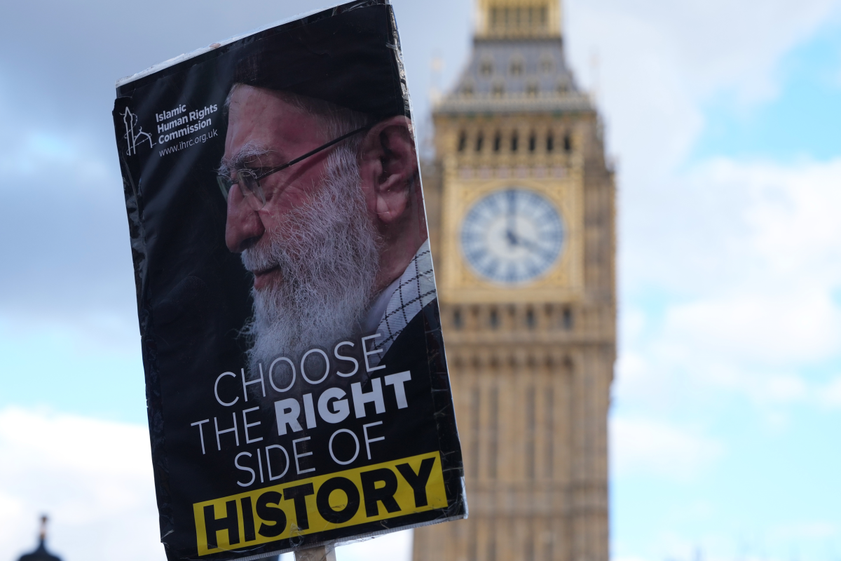 A protester holds a placard in London, Saturday, Feb. 28, 2026 after U.S. and Israeli forces carried out a series of strikes on Iran on Saturday morning.