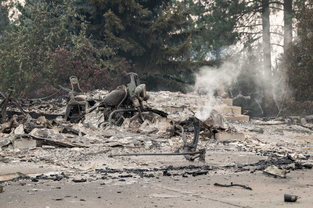 A burned motorcycle sits in the ashes of burned out residential home in the Balboa neighborhood of Spokane, Wash., on August 2, 2026.