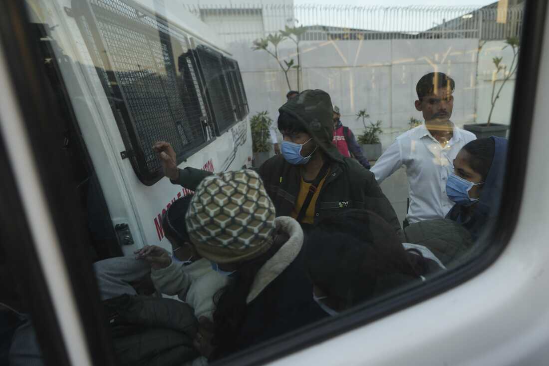 Immigrants, wearing masks, who were among those deported from the United States who arrived in a U.S. military plane in Amritsar, India, enter a police vehicle at India's Ahmedabad airport, Feb. 6.
