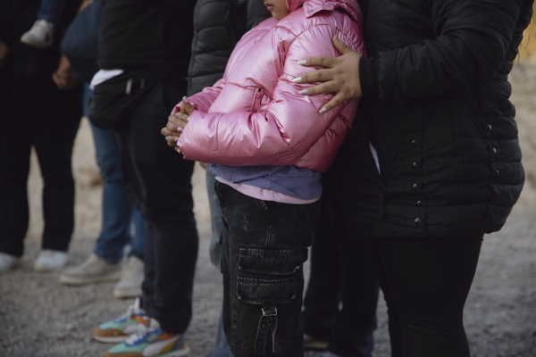A mother holds her daughter after crossing the southern border in Jacumba Valley, California, as Border Patrol agents process the group on Dec. 8, 2024. Zaydee Sanchez for NPR