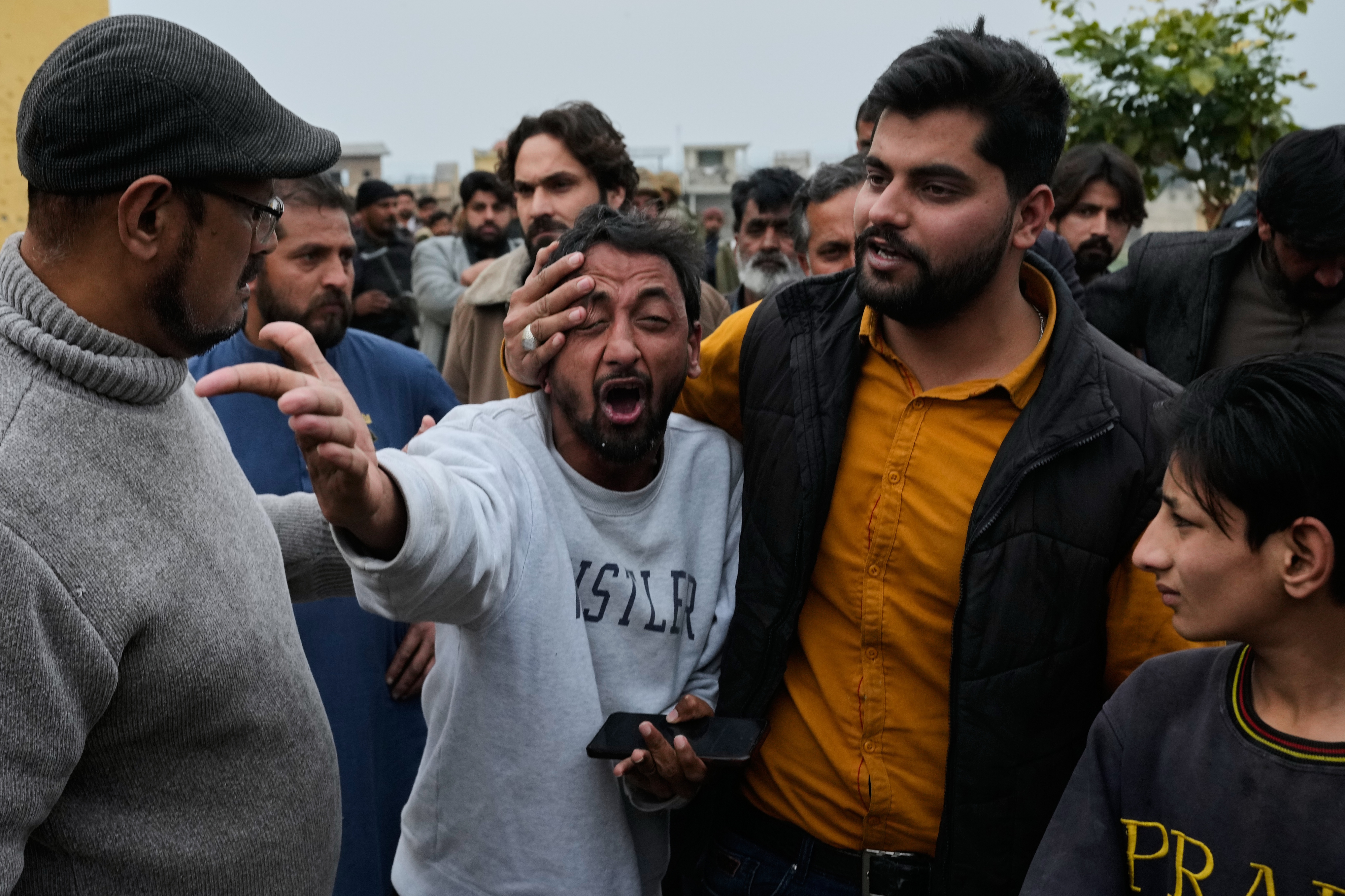 People comfort a man, center, mourning over the death of his relative, close to the site of a bomb explosion at a Shiite mosque, in Islamabad, Pakistan.