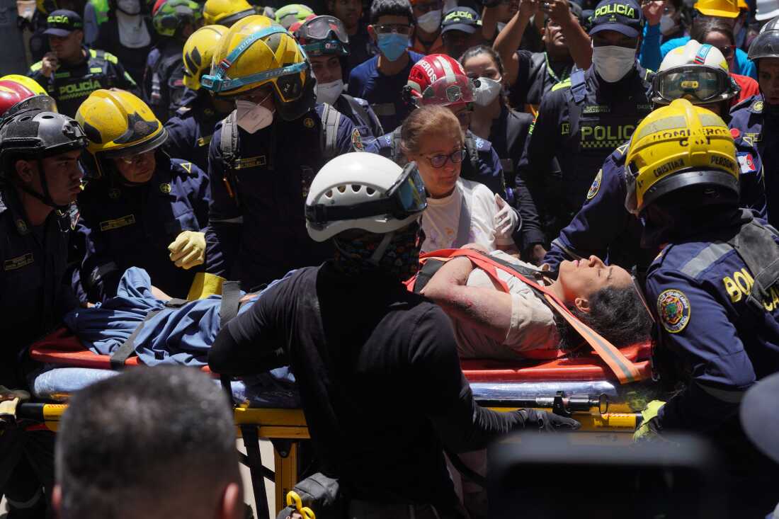 Rescue workers carry Diana Troncoso after pulling her from the rubble the day after an earthquake struck Cali, Colombia, Tuesday, Aug. 11, 2026.