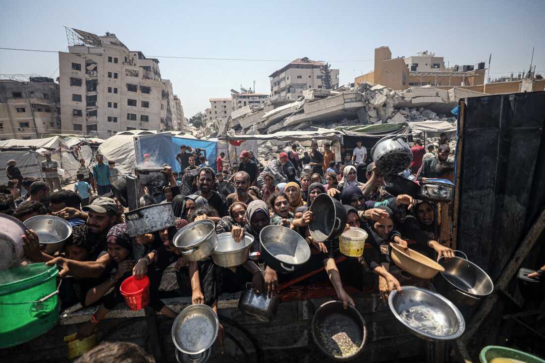  Palestinians carrying pans, gather to receive hot meals, distributed by a charity organization in Gaza City, where residents are struggling to access food due to the ongoing Israeli blockade and attacks in Gaza City, Gaza on July 23, 2025.