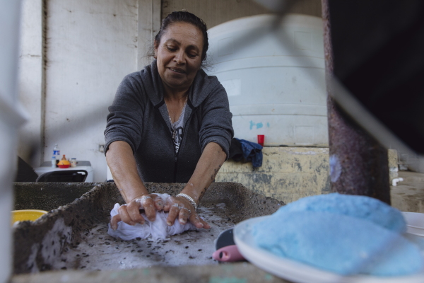 Marta from Michoacán, Mexico, washes clothes at the migrant shelter Embajadores de Jesús church in Tijuana, Mexico, on Dec. 6, 2024. Zaydee Sanchez for NPR.