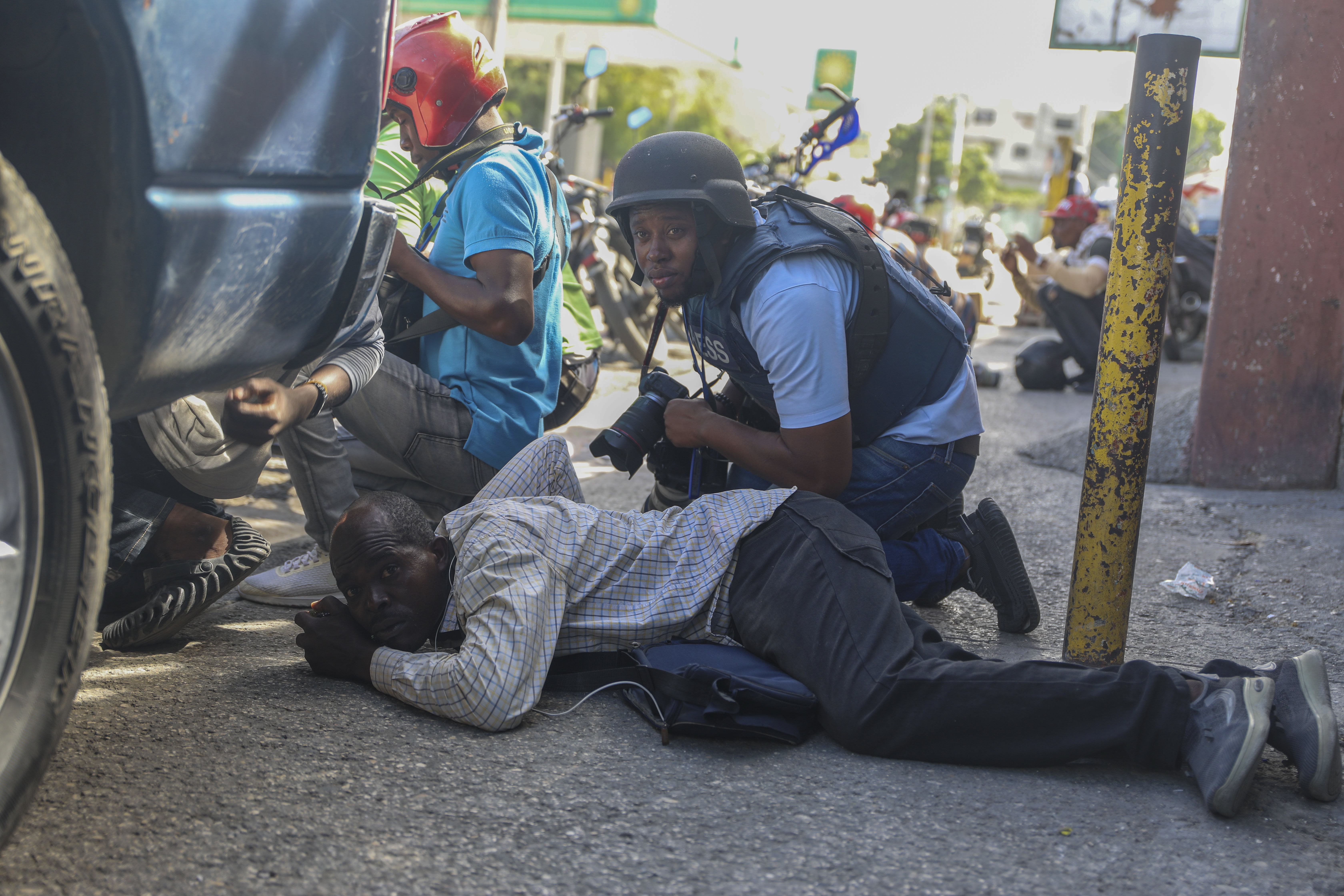 Journalists take cover from the exchange of gunfire between gangs and police in Port-au-Prince, Haiti on Monday. (AP)
