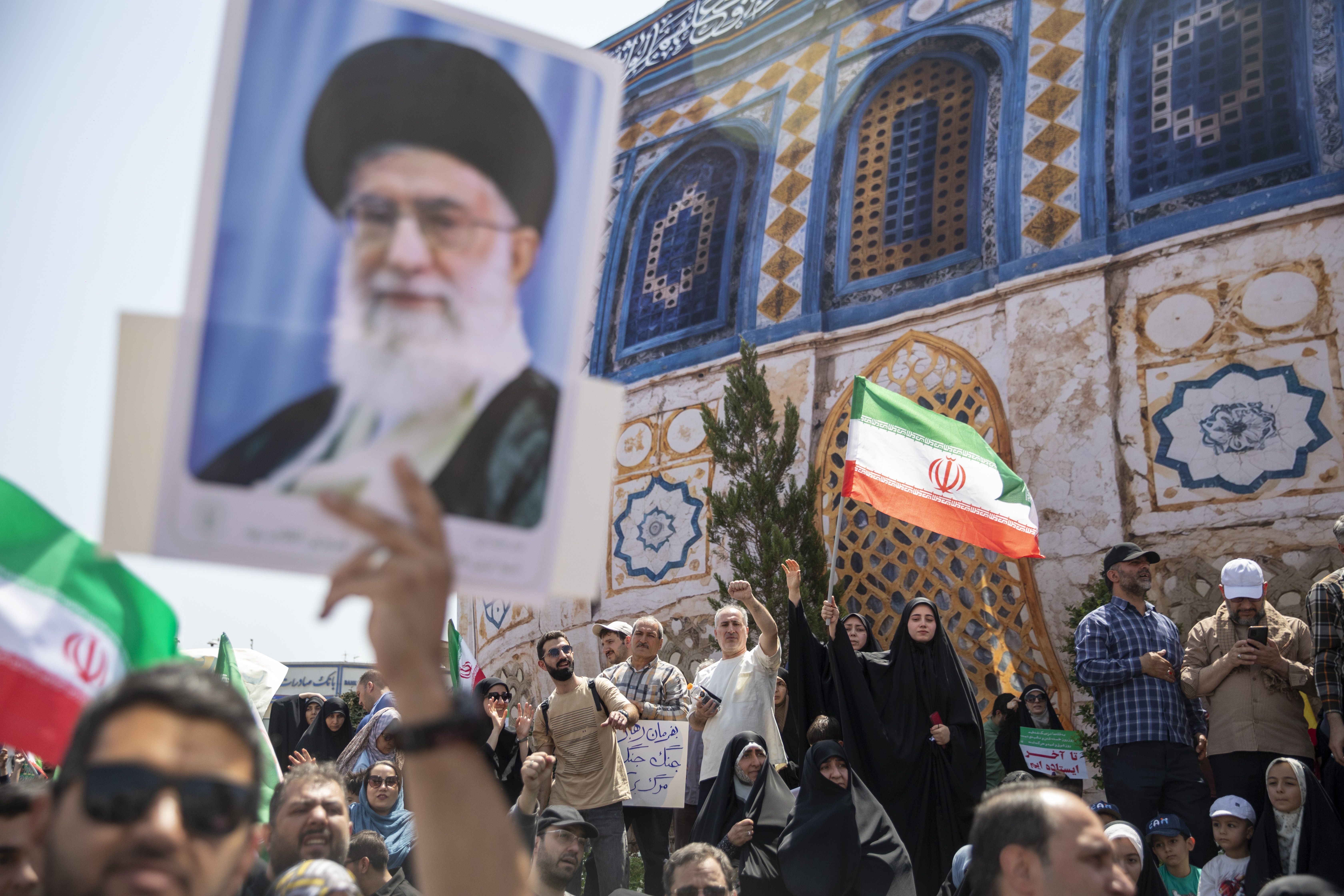 Demonstrators wave Iranian flags as one holds up a poster of Iran