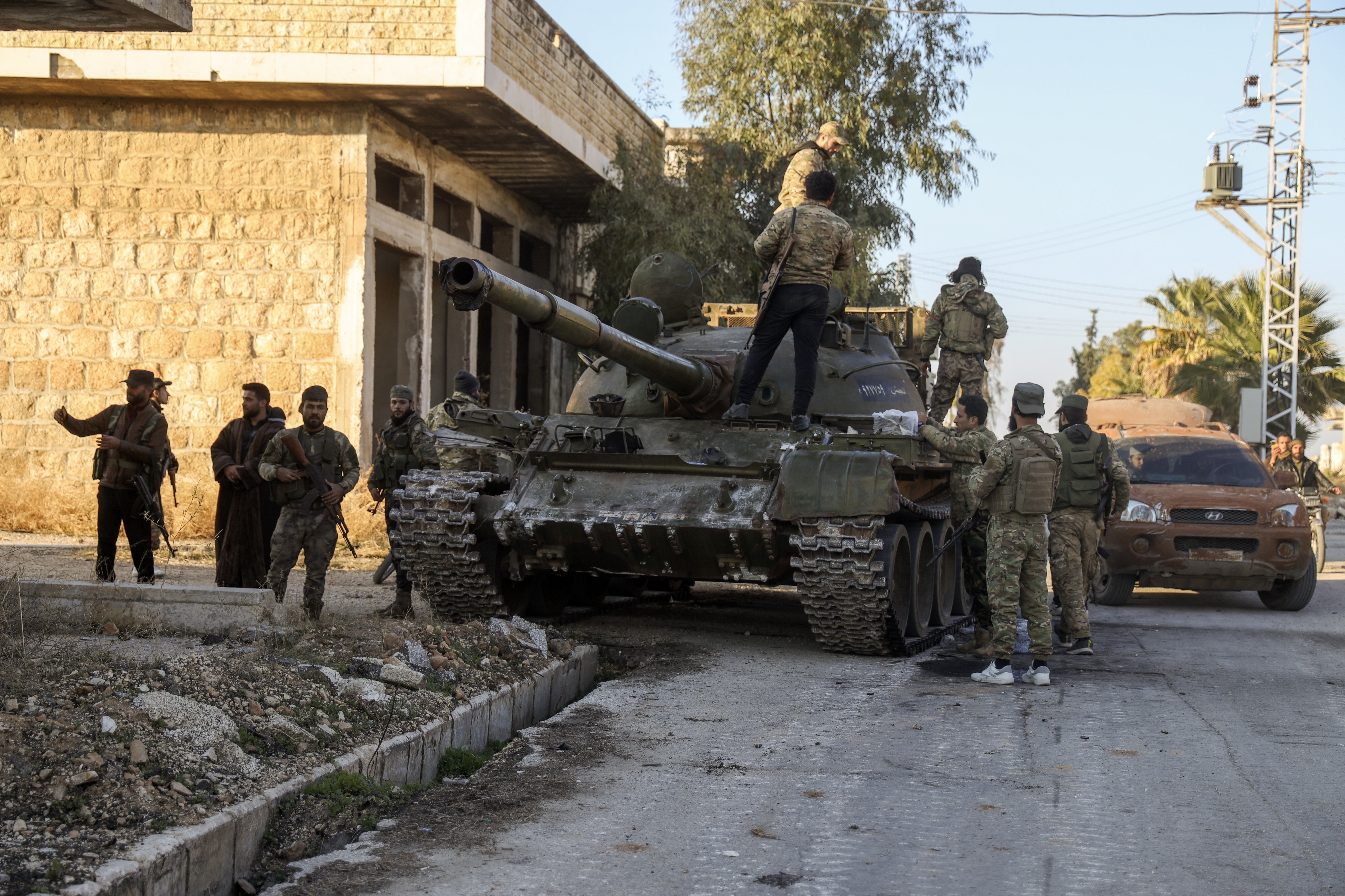 Syrian opposition fighters stand atop a captured Syrian army tank in the town of Maarat al-Numan, southwest from Aleppo, Syria, Saturday.