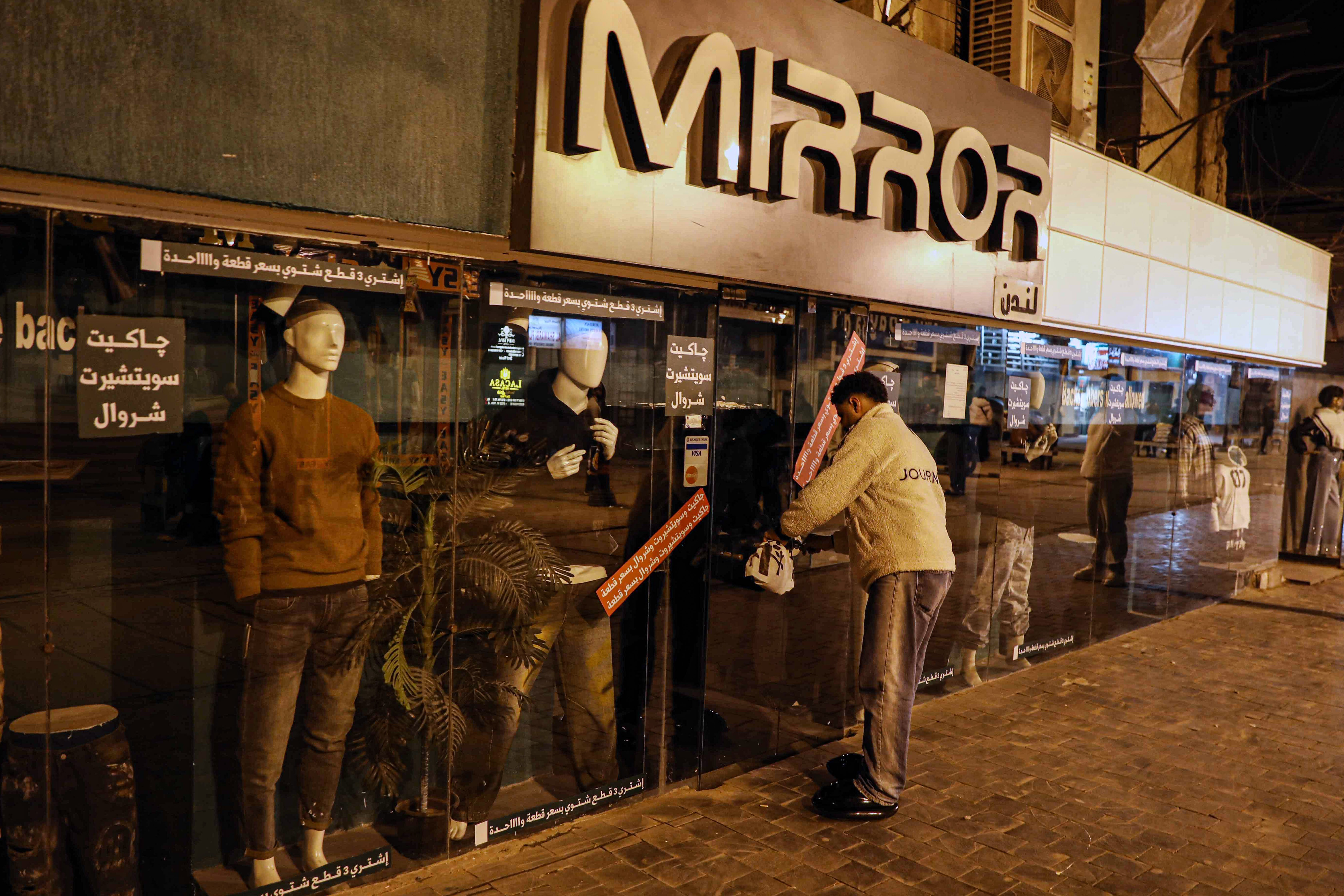 A man closes the door of a shop in Cairo, Egypt, to comply with the government