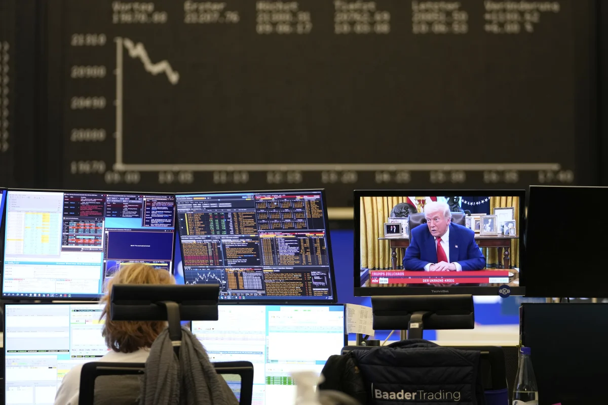 A trader sits in front of computer screens on the trading floor of the Frankfurt Stock Exchange beside a TV showing U.S. President Donald Trump on a news channel in Frankfurt, Germany, on Thursday, the day after Trump announced a 90-day pause on tariffs.
