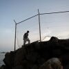 A migrant walks along a rocky shoreline near the border with Morocco after swimming towards Spain's North African enclave of Ceuta on July 31, 2026.