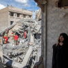 A woman speaks on the phone as emergency workers sift through rubble of a residential building that was hit in an airstrike in the early hours of March 27, 2026 in Tehran, Iran.