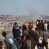 Palestinians watch smoke billowing during Israeli strikes upon arrival on a coastal path northwest of Nuseirat refugee camp.