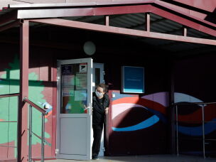 A security person wearing a face mask looks out from the door of an infectious diseases hospital in the town of Shelekhov, where an employee of the Irkutsk Antiplague Research Institute had died.