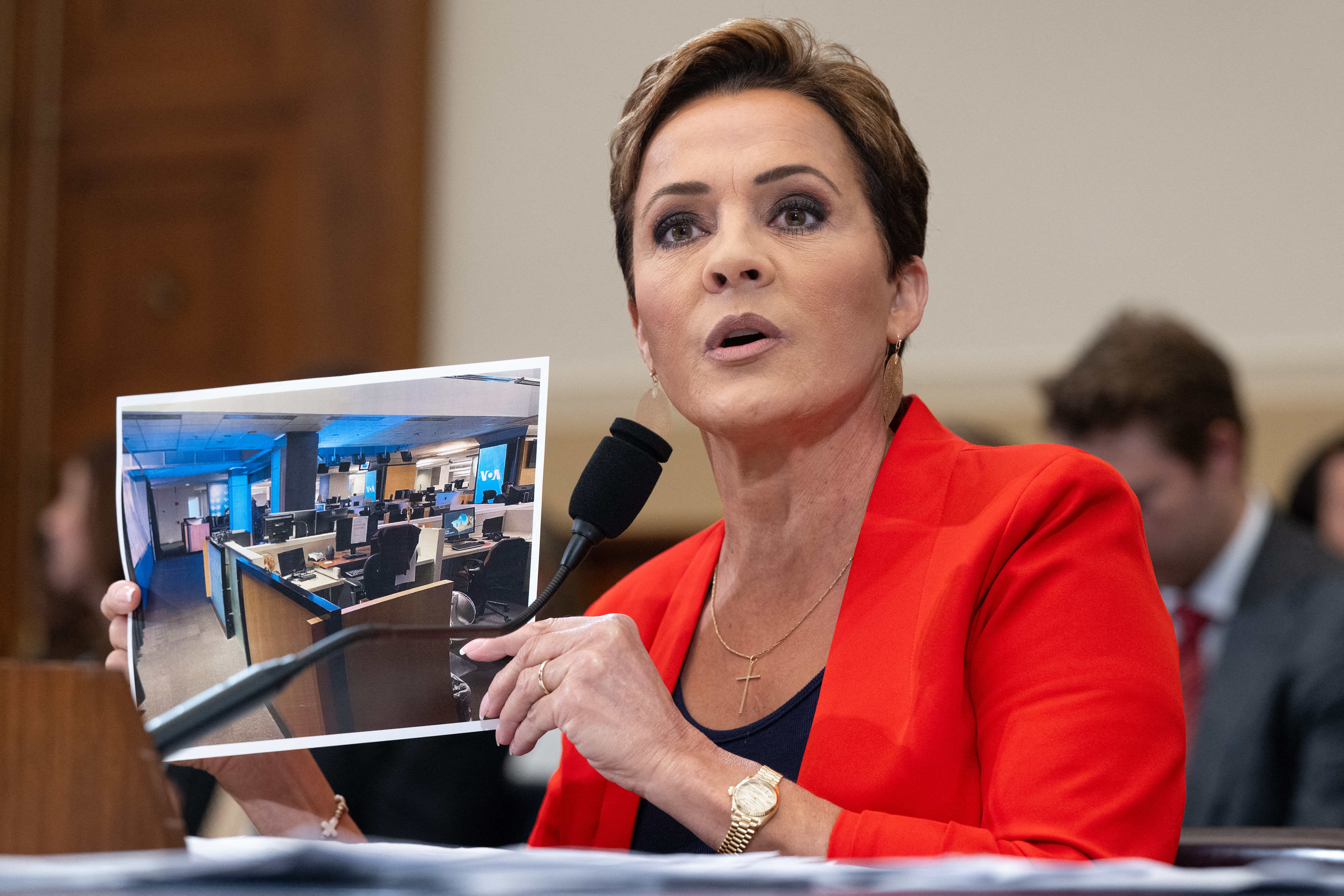 Kari Lake, who is overseeing the U.S. Agency for Global Media, holds up a photo of the Voice of America newsroom as she testifies during a House Foreign Affairs Committee hearing on the future of the agency on June 25, 2025.