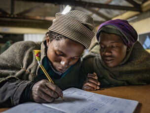 Shepherds Lepeli Maapesa, 23, (left) and Phakiso Phomane, 22, study at the Good Shepherd night school in Semonkong, Lesotho. Maapesa and Phomane both dropped out of formal schooling at a young age when they began working as herders. The Good Shepherd school is one of many night schools around the country striving to provide a basic education to the tens of thousands of shepherd boys and men who missed out on their schooling.