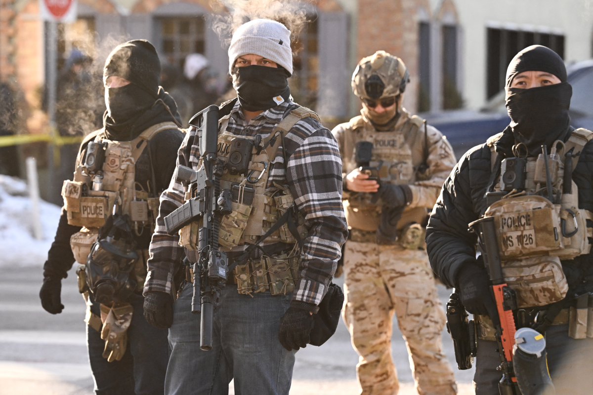 Federal agents look on as demonstrators gather near the site of where Alex Pretti was fatally shot by.