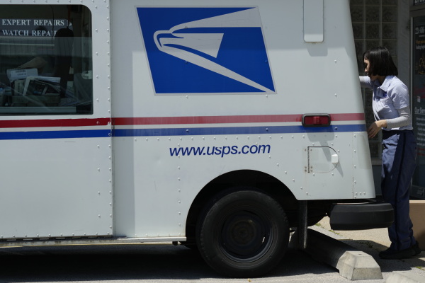 A U.S. Postal Service employee works outside while making deliveries in Northbrook, Ill., in June.