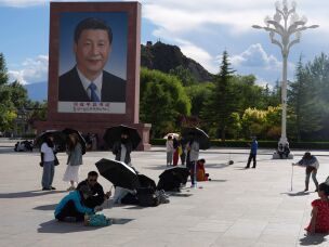 Tourists rest near a portrait of Chinese President Xi Jinping at a public square at the base of the Potala Palace in western China's Tibet autonomous region on July 21, 2026, during a government-organized visit for foreign journalists.