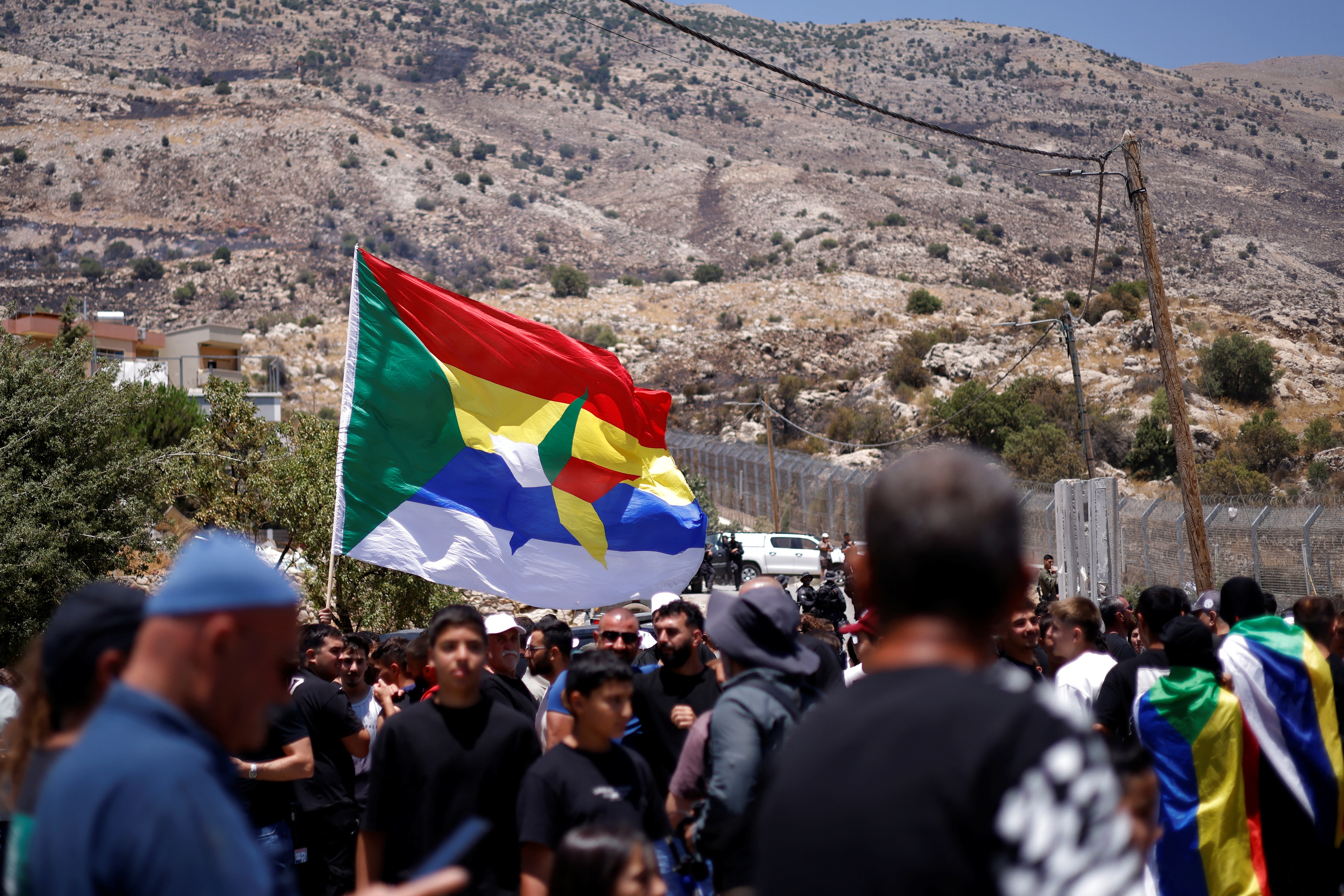 Druze wait near the border fence in the Israeli-annexed Golan Heights village of Majdal Shams, as Syrian Druze who