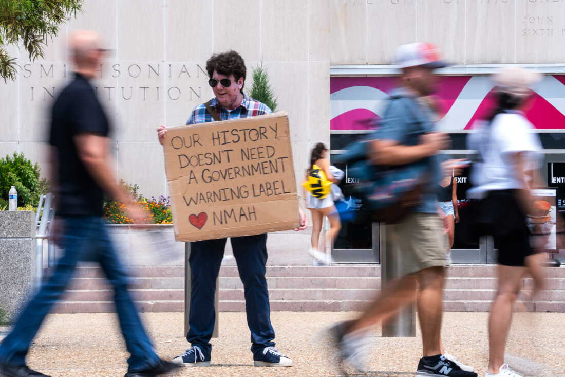 Mark Ehlers holds a sign outside the National Museum of American History in July 2026.