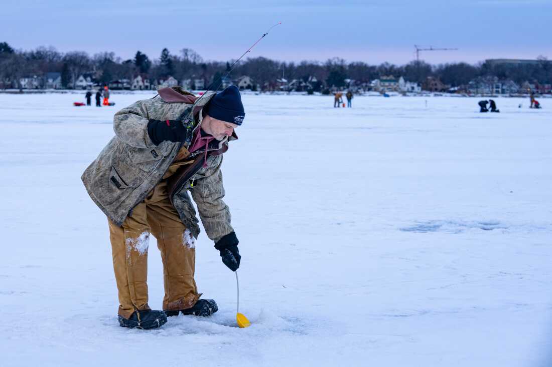 Tony Pavlak scoops slush off the water surface of a hole drilled on Monona Bay while ice fishing on Saturday, Feb. 7, 2026, in Madison, Wisconsin. Photo by Kayla Wolf