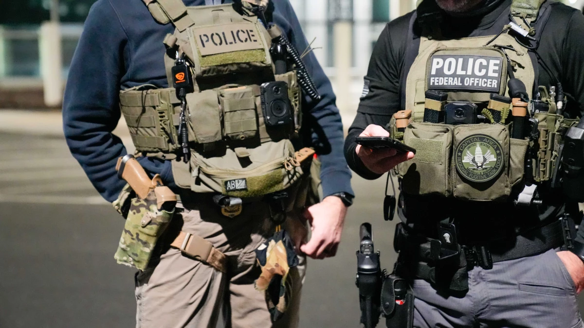 In this handout photo provided by U.S. Immigration and Customs Enforcement, two federal law enforcement officers coordinate with other officials in February 2025 near Washington, D.C.