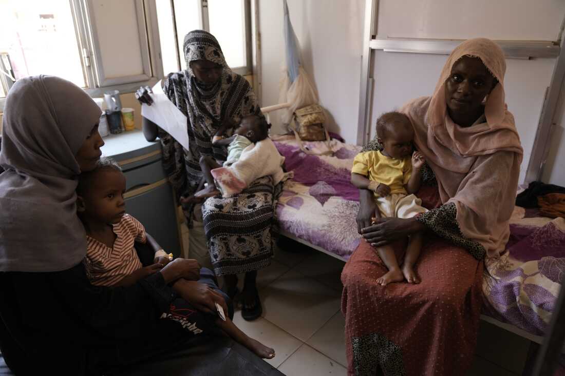 Two women and their children stock a furniture successful a packed malnutrition ward successful Al Buluk.