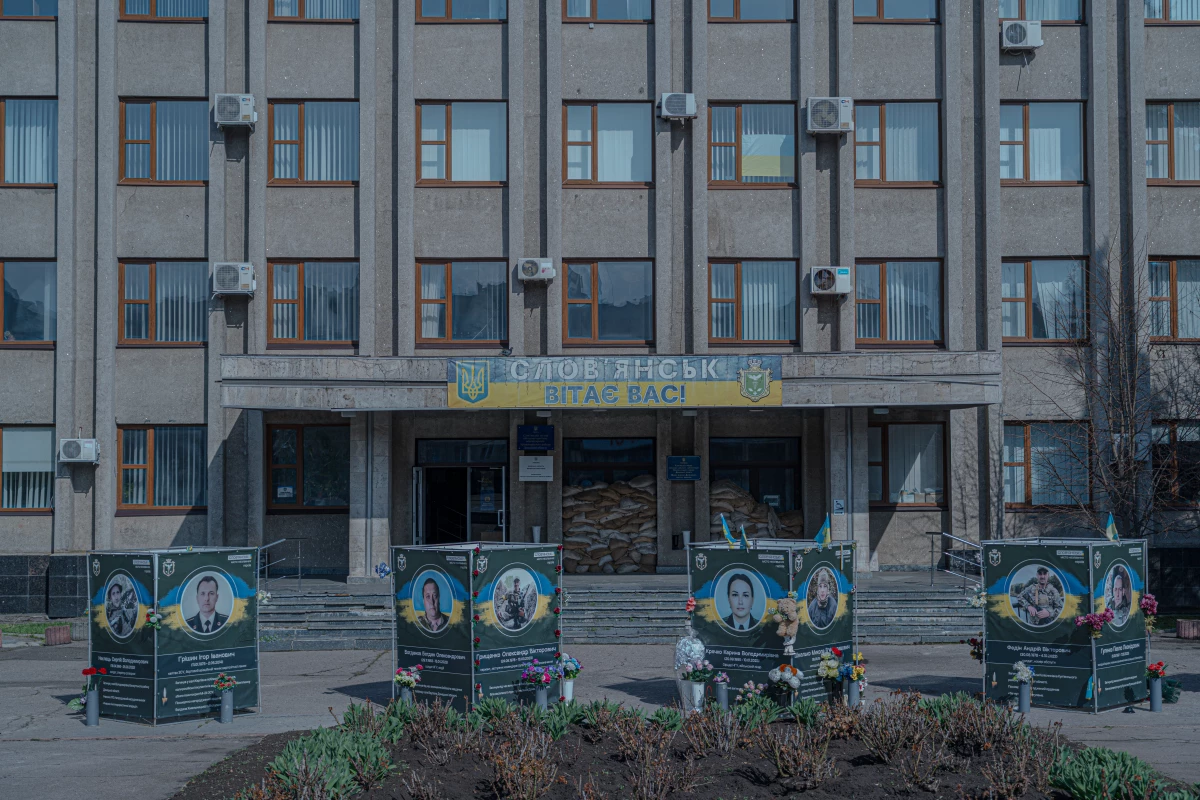 The Alley of Memory memorial sits in front of the Sloviansk City Administration building. A sign at the entrance reads, 'Sloviansk welcomes you!'