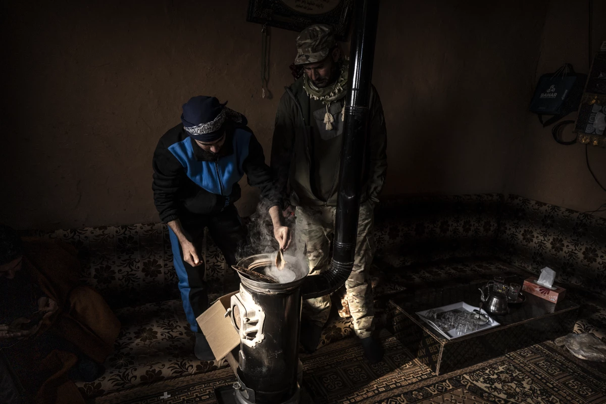 Displaced Syrians, one a member of the U.S.-backed Syrian Free Army, light the stove in one of one of hundreds of mud-brick houses that make up the Rukban camp, Dec. 14.