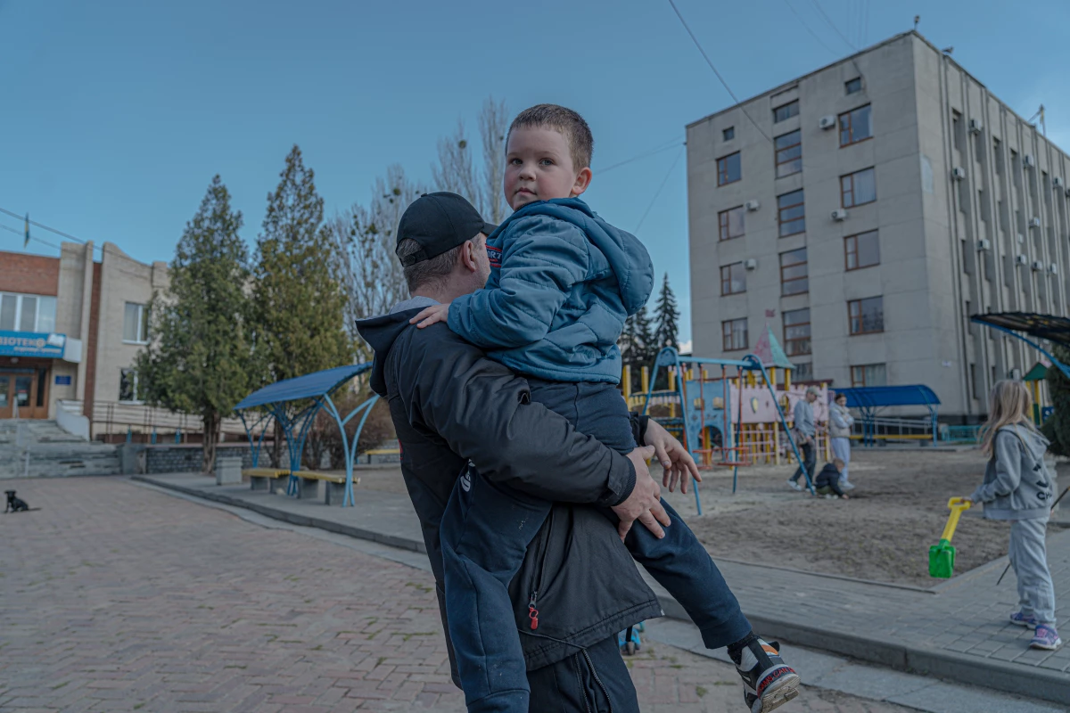 Dmytro Kluchnikov holds his son Artem in his arms at a playground in the center of Sloviansk.