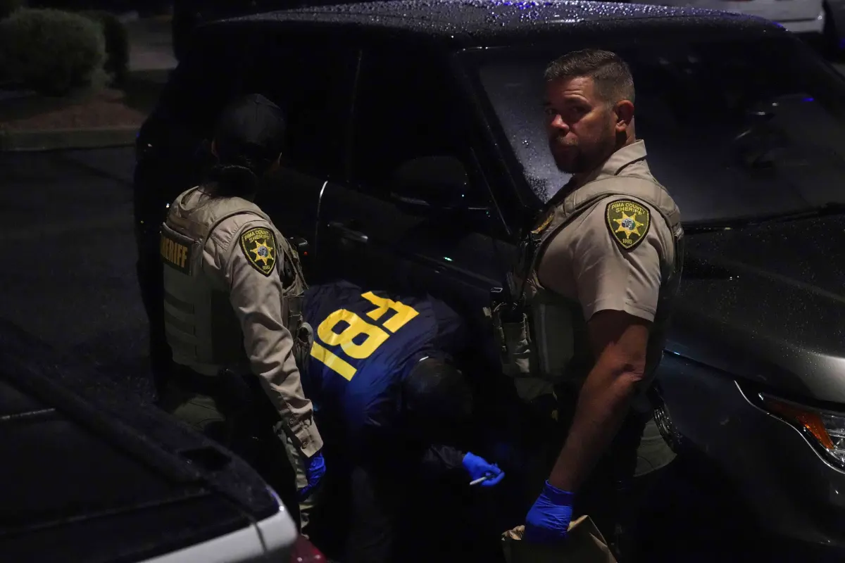 Law enforcement from the Pima County Sheriff's Department and the FBI work on a Range Rover in a Culver's parking lot in Tucson, Ariz., early Saturday.