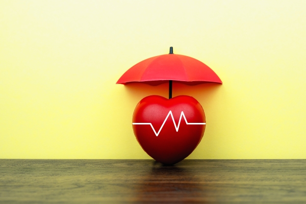 A photo illustration shows an apple with an EKG line across it, covered by an umbrella.