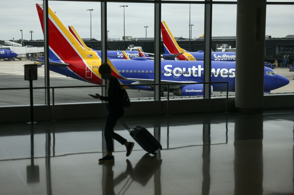 A traveler walks past a Southwest Airlines airplane as it taxis at Baltimore Washington International Thurgood Marshall Airport on October 11, 2021 in Baltimore.