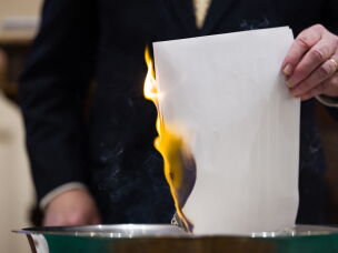 The Rev. John Jackman burns a list of names of people in surrounding Forsyth County whose debt was purchased and retired by the church.