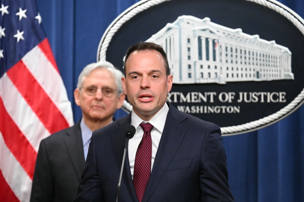 Benjamin Mizer, with Attorney General Merrick Garland (L), speaks during a press conference announcing an antitrust lawsuit against Apple in March 2024.
