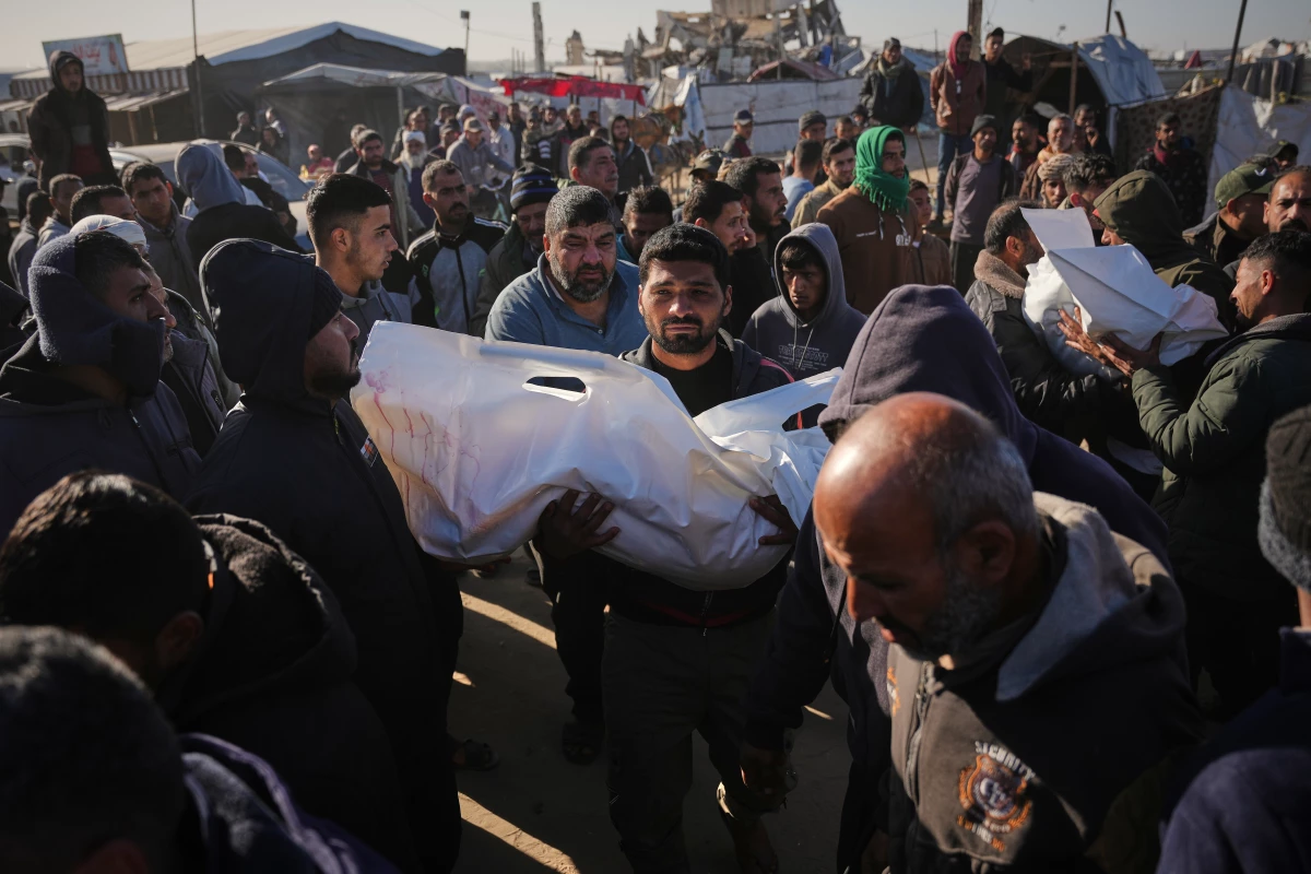 A Palestinian man carries the body of Sham Abu Hadaiyd, who was killed in an Israeli strike on a tent in Khan Younis, Gaza Strip, Saturday, Jan. 31, 2026.