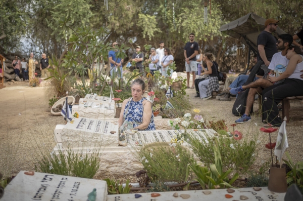 A woman sits next to a grave at the Nir Oz Kibbutz cemetery during a ceremony commemorating the 2 year anniversary of the 7th of October Hamas led attack.