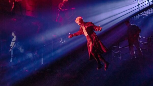 A scene from “The Lost Boys” showing a man suspended in the air with the spotlight on him. 