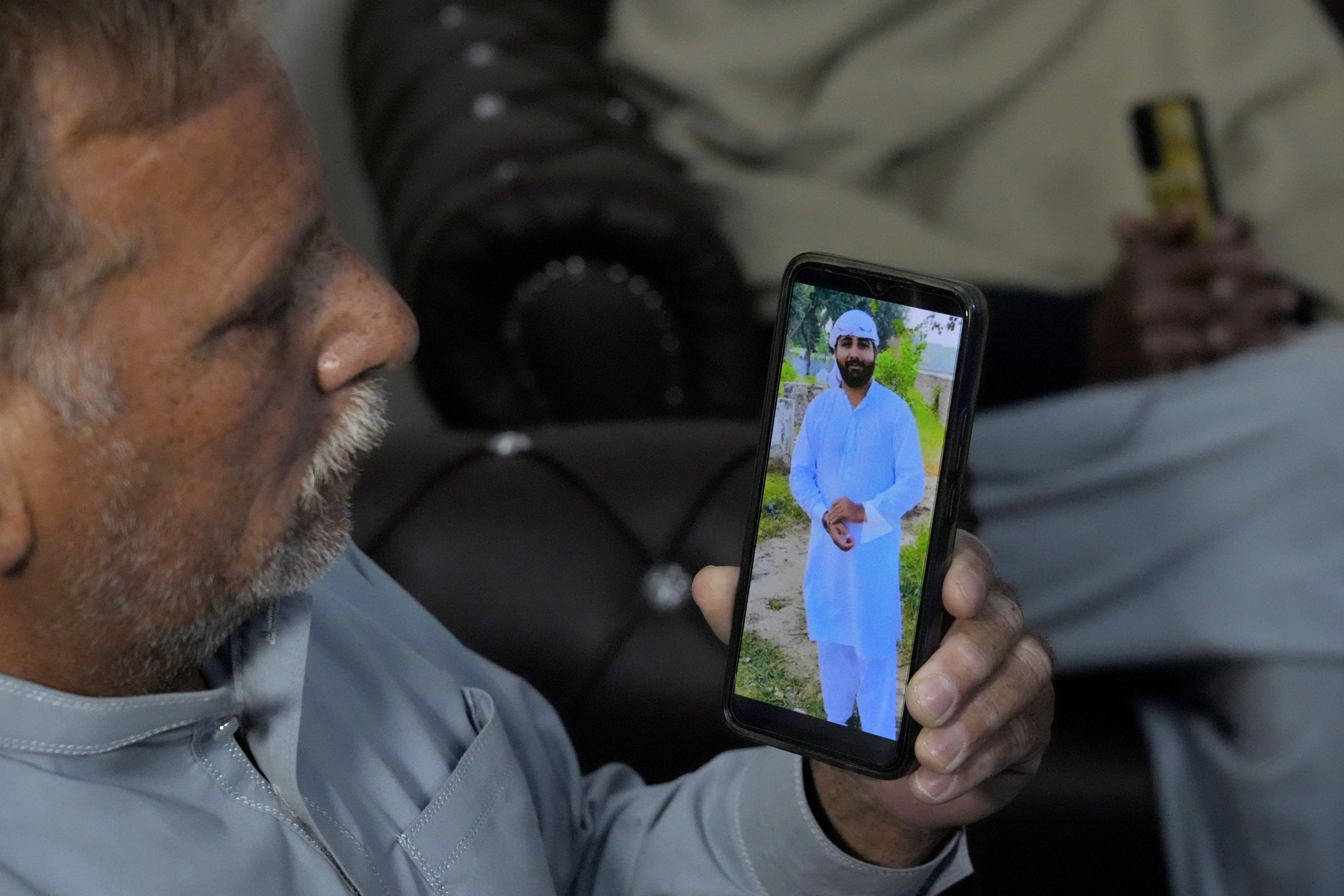 A Pakistani Mohammad Akram shows a picture of his son Abu Bakar, one of the victims of a migrant boat that capsized in West Africa