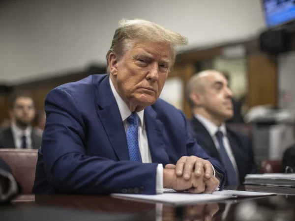 Former president Trumps looks directly into the camera sitting at a courthouse.