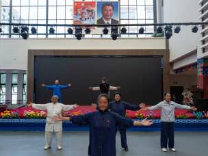 Elderly residents perform tai chi near the portrait of Chinese President Xi Jinping and other Chinese leaders at the Chengguan District Day Care Center for the Elderly in western China's Tibet autonomous region on July 20, 2026, as seen during a government-organized visit for foreign journalists.