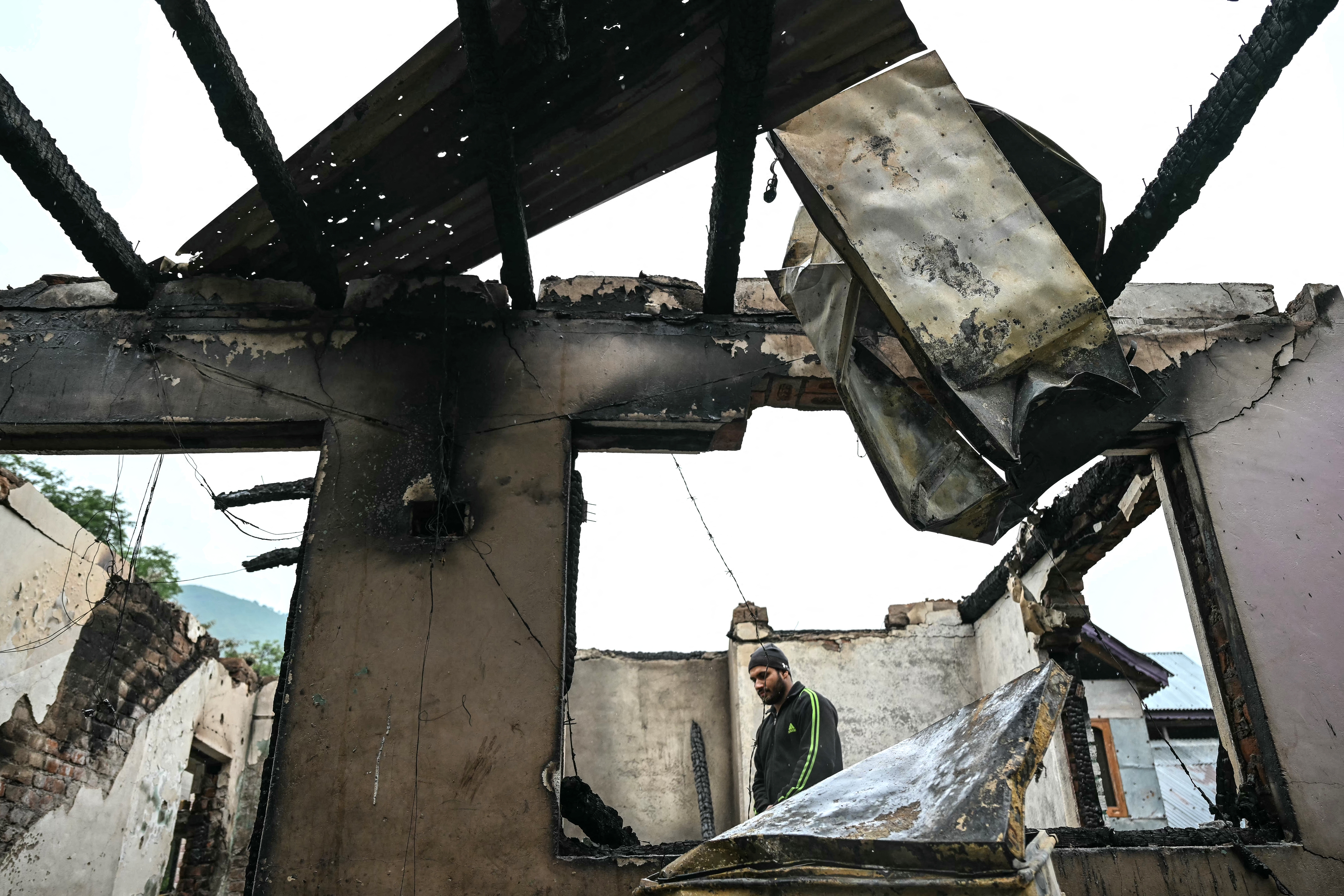 A man stands inside his house destroyed by Pakistani artillery shelling in the village of Salamabad, India, Thursday.