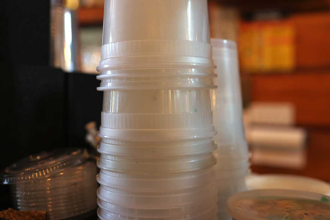 In this photo, a tower of plastic takeout tubs stacked into one another stands upside down.